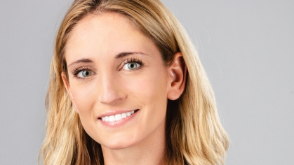 Headshot of a woman with shoulder length blond hair smiling, wearing a blue and green top.