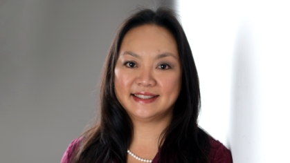 Headshot of woman with black hair, wearing a burgundy suit jacket, black shirt, and pearl necklace.