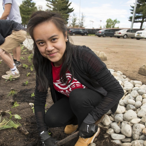 Young woman with long brown hair planting vegetation.