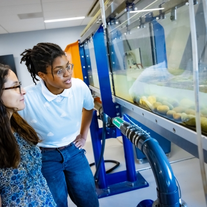 Two female students looking at lab equipment that simulates water flow.