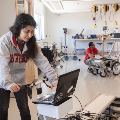 Three students working in a lab that features road testing equipment.