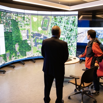 Professor and graduate student sharing mapping research on large circular screen