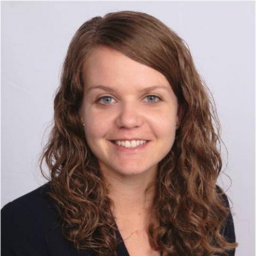 head shot of female with curly long brown hair wearing a black suit jacket