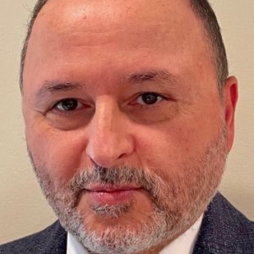 head shot of man with beard, short brown hair, wearing a dark blue suit, white shirt, and tie