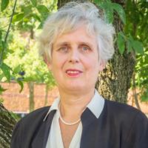 head shot of woman with short grey hair wearing a dark grey suit, white blouse, and pearl necklace.