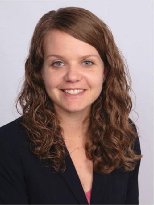 head shot of female with curly long brown hair wearing a black suit jacket