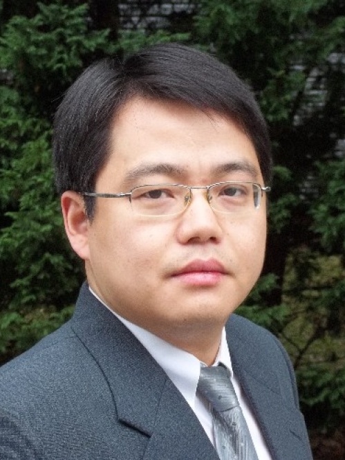 head shot of asian man with short black hair and eyeglasses wearing a grey suit, grey tie, and a white shirta