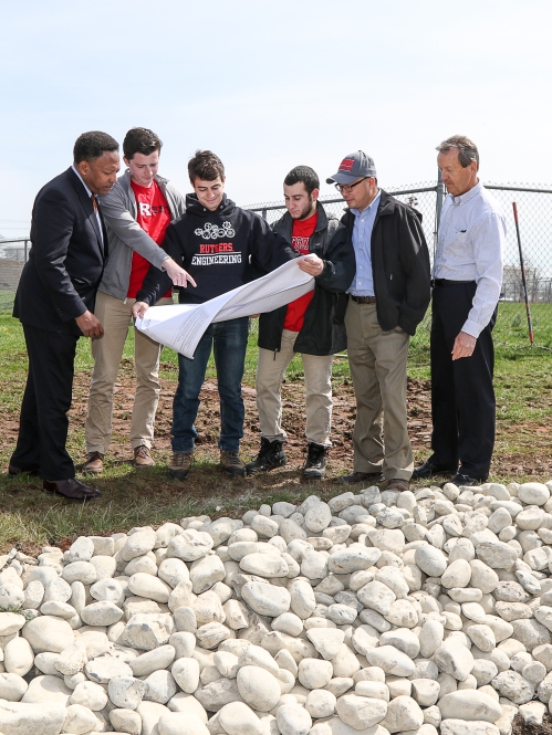 Six individuals reviewing plans outdoors to assess installation of a natural water filter to restore flooding in wetlands. 