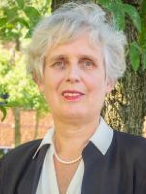 head shot of woman with short grey hair wearing a dark grey suit, white blouse, and pearl necklace.