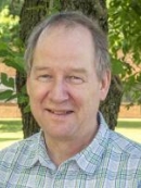 head shot of male with receeding hairline standing under a tree