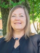 head shot of woman with shoulder length blonde hair wearing a black suit jacket and necklace