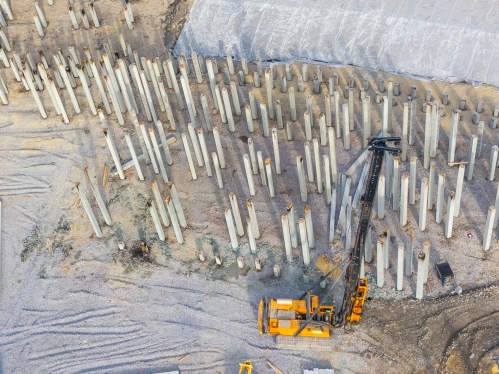 Equipment for installing piles in ground, heavy machines for driving pillars work in laying the foundation building. Construction aerial view height.