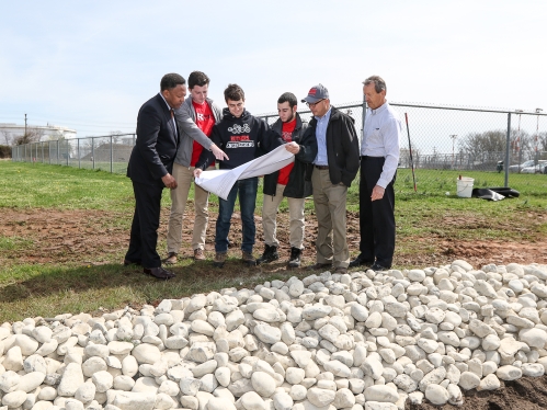 Six individuals reviewing plans outdoors to assess installation of a natural water filter to restore flooding in wetlands.
