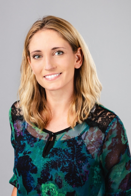 Headshot of a woman with shoulder length blond hair smiling, wearing a blue and green top.